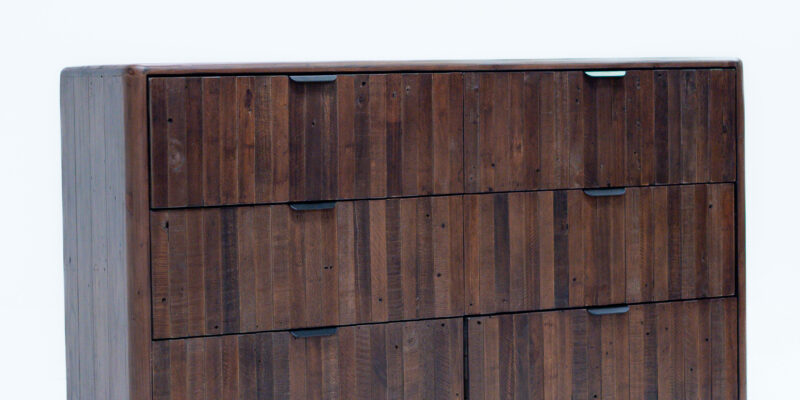 A modern wooden dresser with a dark brown finish featuring a six-drawer design with black metal handles. The dresser stands on four slightly tapered black legs, and the wood grain is visible, adding texture and character. The background is a plain white surface.